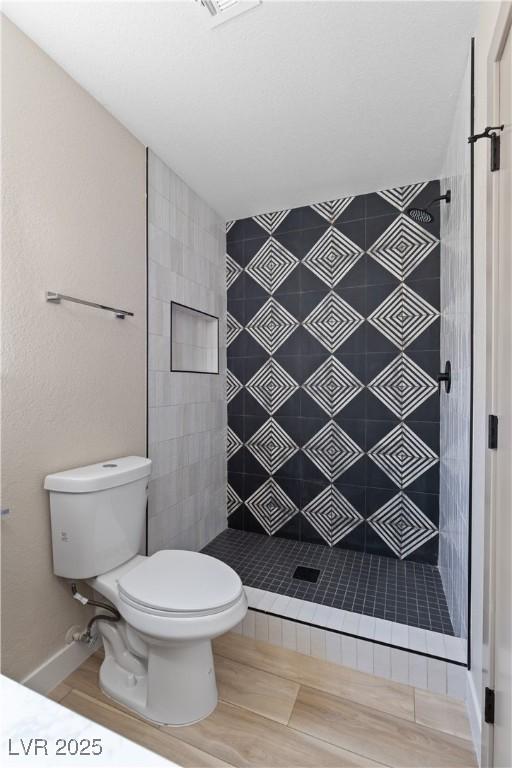 bathroom featuring a shower stall, toilet, and wood finished floors