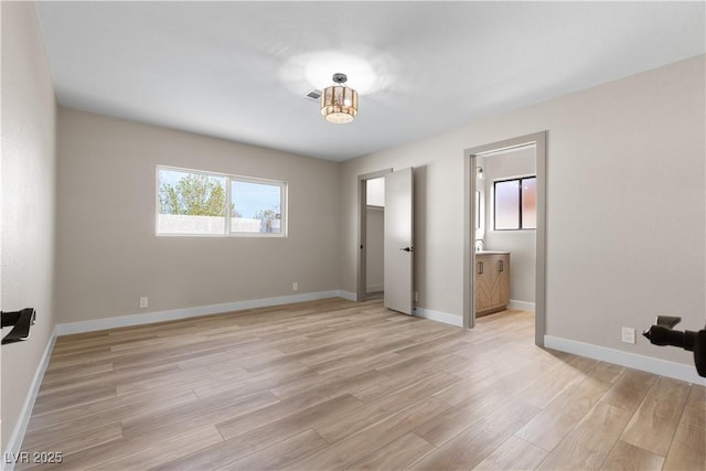 unfurnished bedroom with visible vents, ensuite bathroom, light wood-type flooring, and baseboards