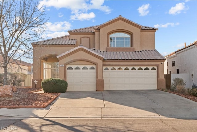 mediterranean / spanish house with stucco siding, a tiled roof, concrete driveway, and fence