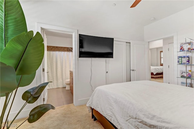 tiled bedroom featuring carpet flooring, a ceiling fan, a closet, and ensuite bathroom