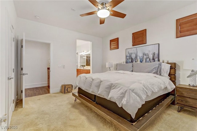 bedroom with baseboards, light colored carpet, connected bathroom, and a ceiling fan