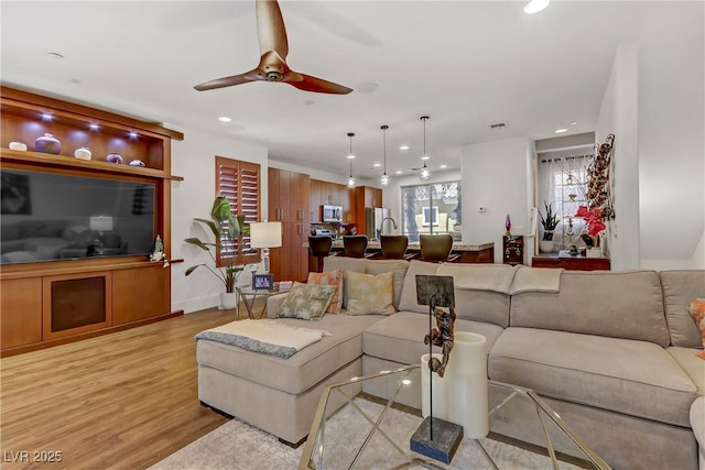 living room featuring a ceiling fan, recessed lighting, and light wood-style floors