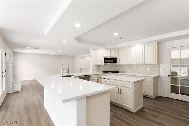 3021 Ocean Port Dr, Las Vegas, NV 89117 - kitchen featuring stainless steel dishwasher, a peninsula, wood finished floors, a sink, and backsplash
