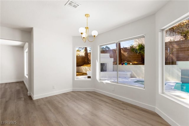 unfurnished dining area with visible vents, baseboards, and wood finished floors