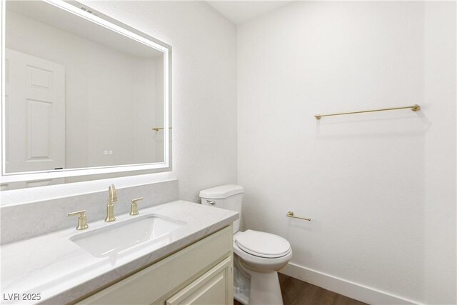 bathroom with baseboards, toilet, wood finished floors, and vanity