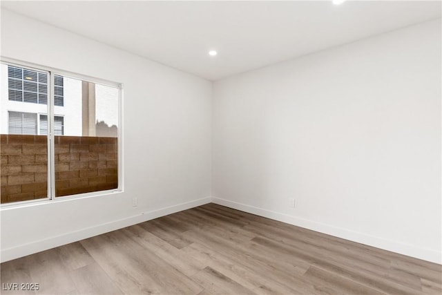 unfurnished room featuring recessed lighting, wood finished floors, and baseboards