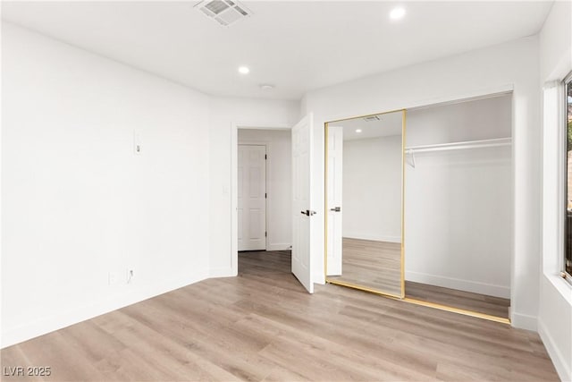 unfurnished bedroom featuring visible vents, baseboards, light wood-style flooring, recessed lighting, and a closet