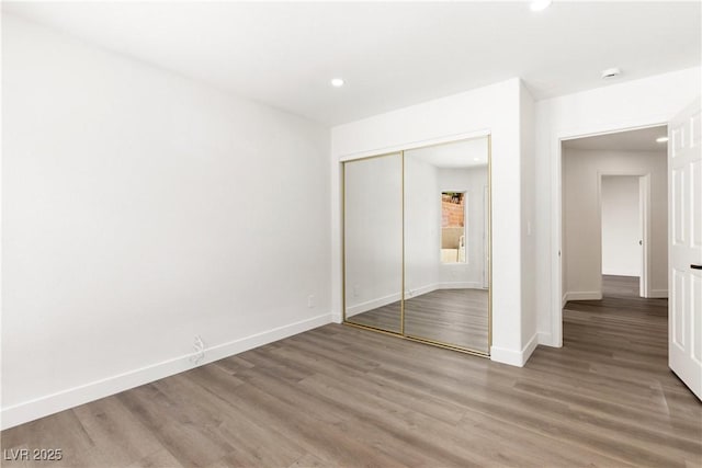 unfurnished bedroom with a closet, recessed lighting, baseboards, and light wood finished floors