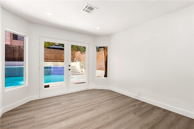 empty room with visible vents, wood finished floors, recessed lighting, french doors, and baseboards