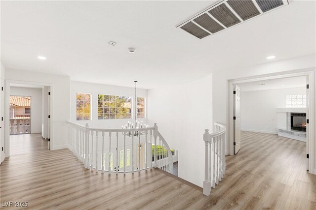 corridor featuring visible vents, an upstairs landing, and wood finished floors