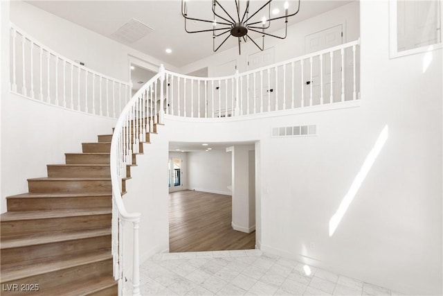 stairway with visible vents, a notable chandelier, recessed lighting, a high ceiling, and baseboards