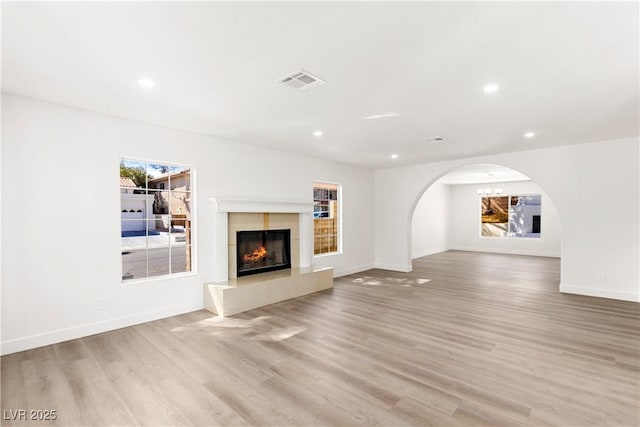 unfurnished living room with a high end fireplace, visible vents, recessed lighting, and light wood-type flooring