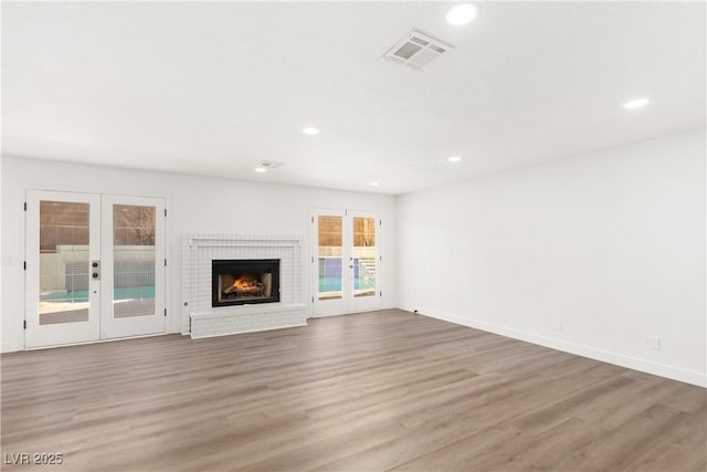 unfurnished living room featuring visible vents, recessed lighting, french doors, and wood finished floors