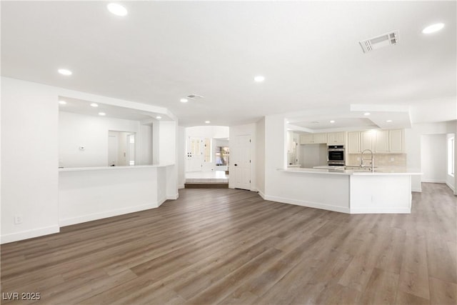 unfurnished living room with a sink, visible vents, light wood-type flooring, and recessed lighting