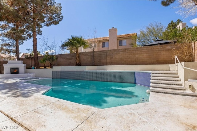 view of pool featuring a fenced backyard, a patio area, a lit fireplace, and a fenced in pool