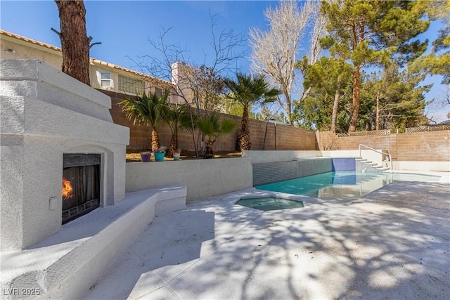 view of pool featuring a fenced in pool, a patio, a lit fireplace, and a fenced backyard