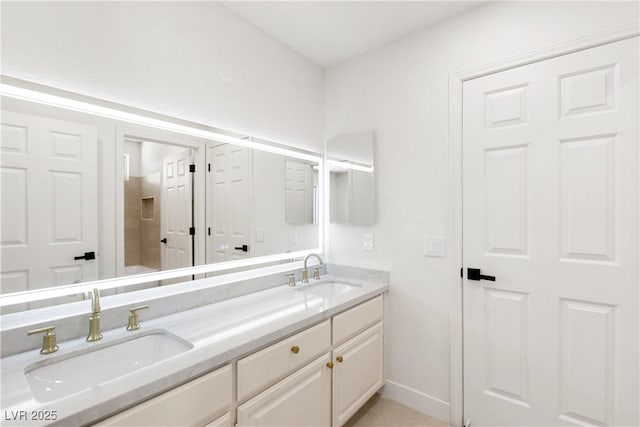 full bathroom featuring double vanity, baseboards, and a sink