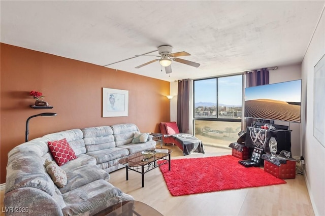 living room with ceiling fan, expansive windows, and wood finished floors