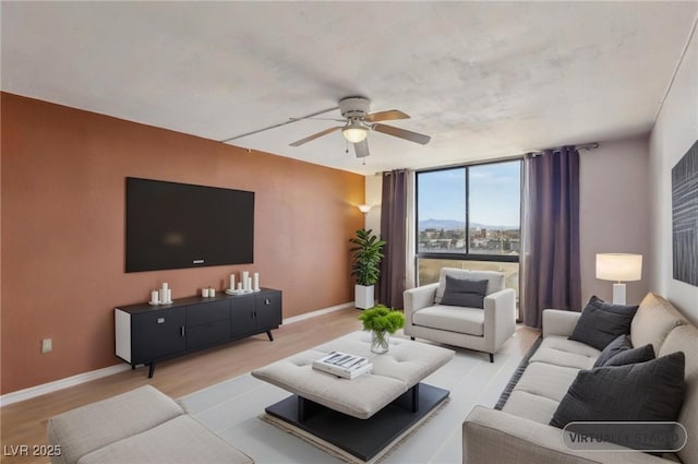 living area with ceiling fan, expansive windows, baseboards, and wood finished floors