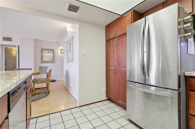 kitchen with light tile patterned floors, visible vents, stainless steel appliances, and light stone countertops