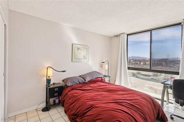 bedroom with access to exterior, baseboards, expansive windows, tile patterned floors, and a textured ceiling