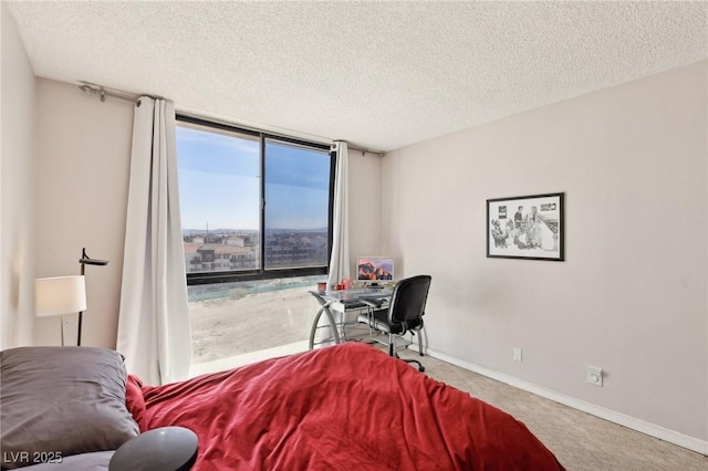 carpeted bedroom featuring a wall of windows, baseboards, a textured ceiling, and access to outside