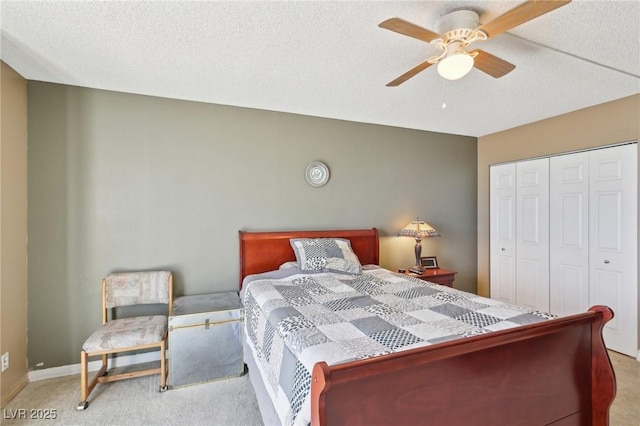 carpeted bedroom with a closet, baseboards, a textured ceiling, and ceiling fan