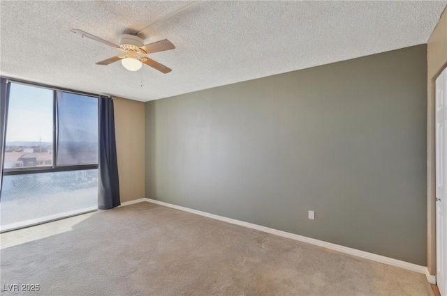 unfurnished room with carpet flooring, a ceiling fan, a wall of windows, and baseboards