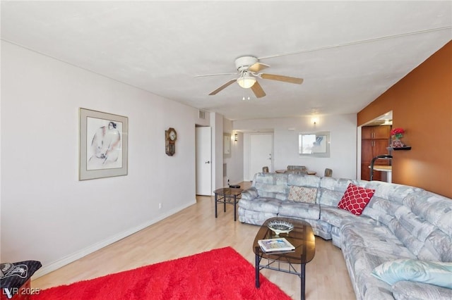 living room with baseboards, a ceiling fan, and wood finished floors