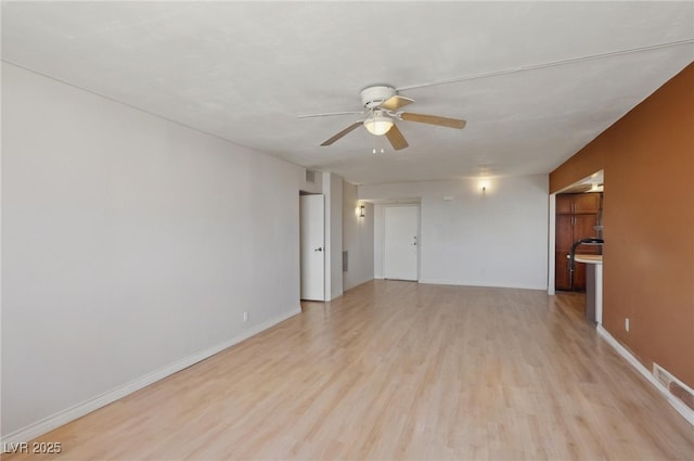 unfurnished room with baseboards, a ceiling fan, and light wood-style floors