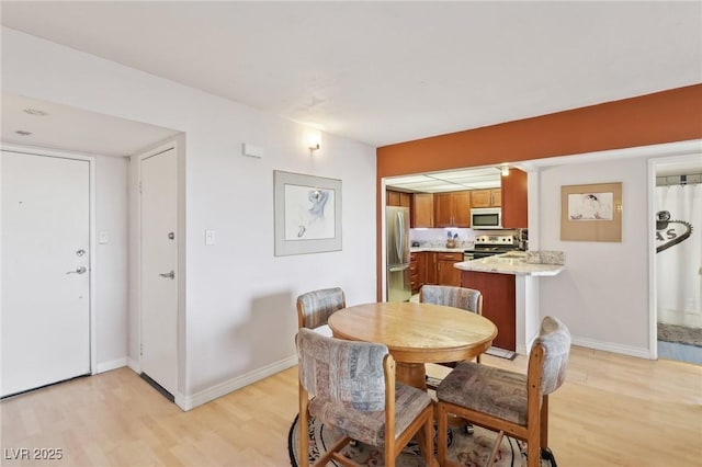 dining space featuring light wood-style floors and baseboards