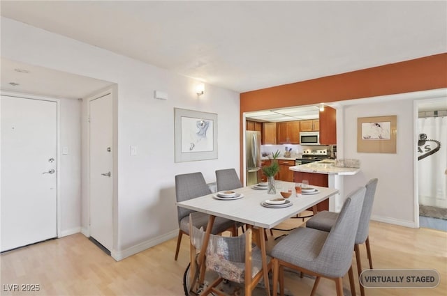 dining space with light wood-style flooring and baseboards