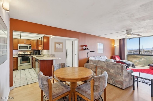 dining area with light wood-type flooring, ceiling fan, and expansive windows