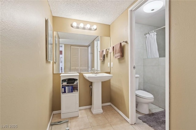 bathroom with a shower with curtain, baseboards, a textured ceiling, tile patterned floors, and toilet