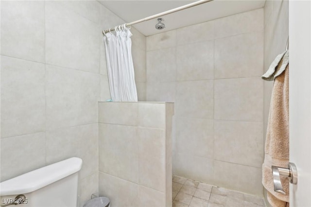 bathroom with tile walls, toilet, and a tile shower