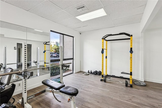 workout area featuring visible vents, wood finished floors, baseboards, and a drop ceiling