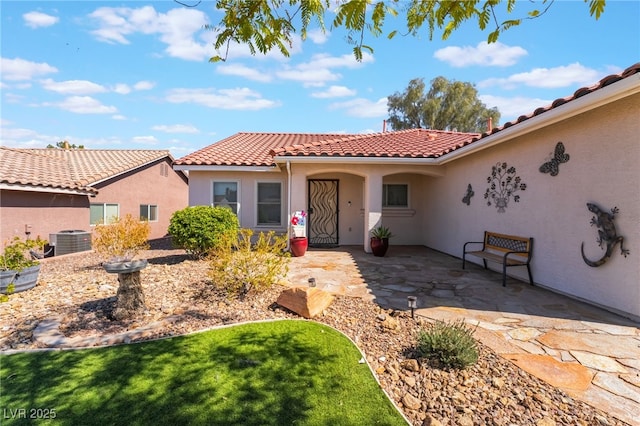 view of front of property featuring stucco siding, central air condition unit, a patio area, and a tile roof