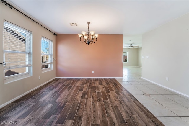 spare room with visible vents, baseboards, wood finished floors, and ceiling fan with notable chandelier