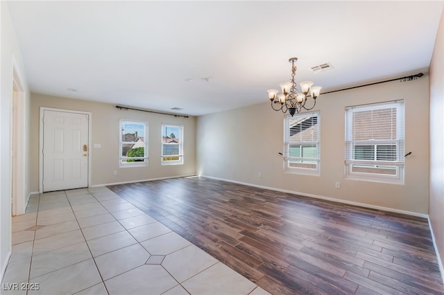 interior space with light wood-type flooring, baseboards, visible vents, and a chandelier