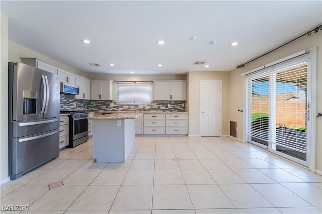 kitchen with backsplash, a kitchen island, recessed lighting, appliances with stainless steel finishes, and light tile patterned flooring