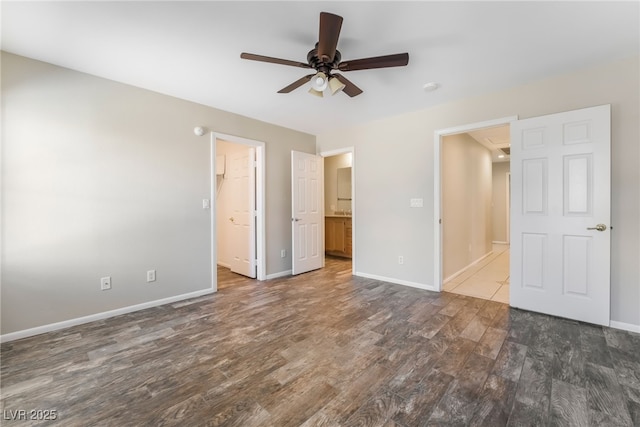 unfurnished bedroom with a ceiling fan, dark wood-style floors, baseboards, and connected bathroom