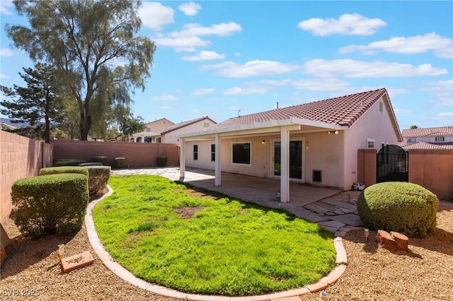 rear view of house with a gate, a fenced backyard, stucco siding, a tile roof, and a patio area