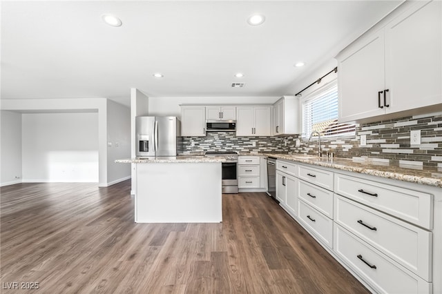 206 Lynbrook St, Henderson, NV 89012 - kitchen with appliances with stainless steel finishes, decorative backsplash, a center island, dark wood-style flooring, and recessed lighting