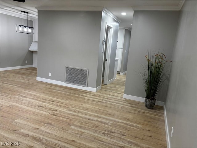 interior space featuring visible vents, baseboards, light wood-style flooring, and crown molding