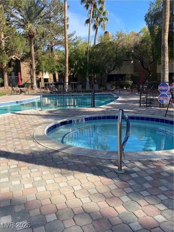 pool featuring a patio, fence, and a hot tub