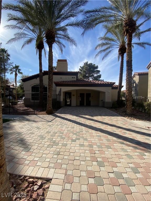 back of property with fence, a chimney, driveway, and stucco siding