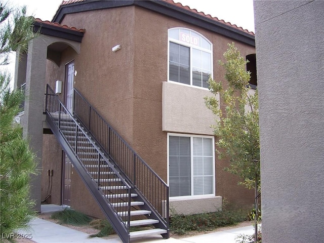 exterior space with stucco siding, stairs, and a tiled roof