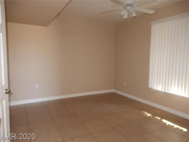 empty room featuring tile patterned flooring, baseboards, and a ceiling fan