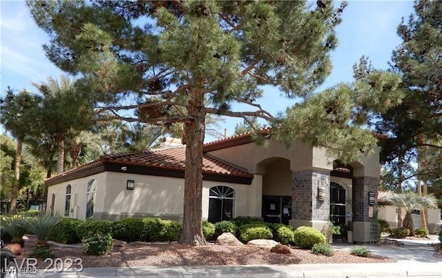 mediterranean / spanish-style home featuring a tile roof, central AC, and stucco siding