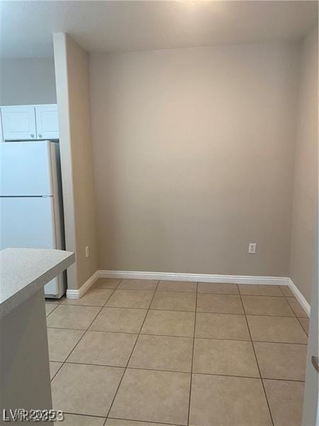 unfurnished dining area with light tile patterned flooring and baseboards